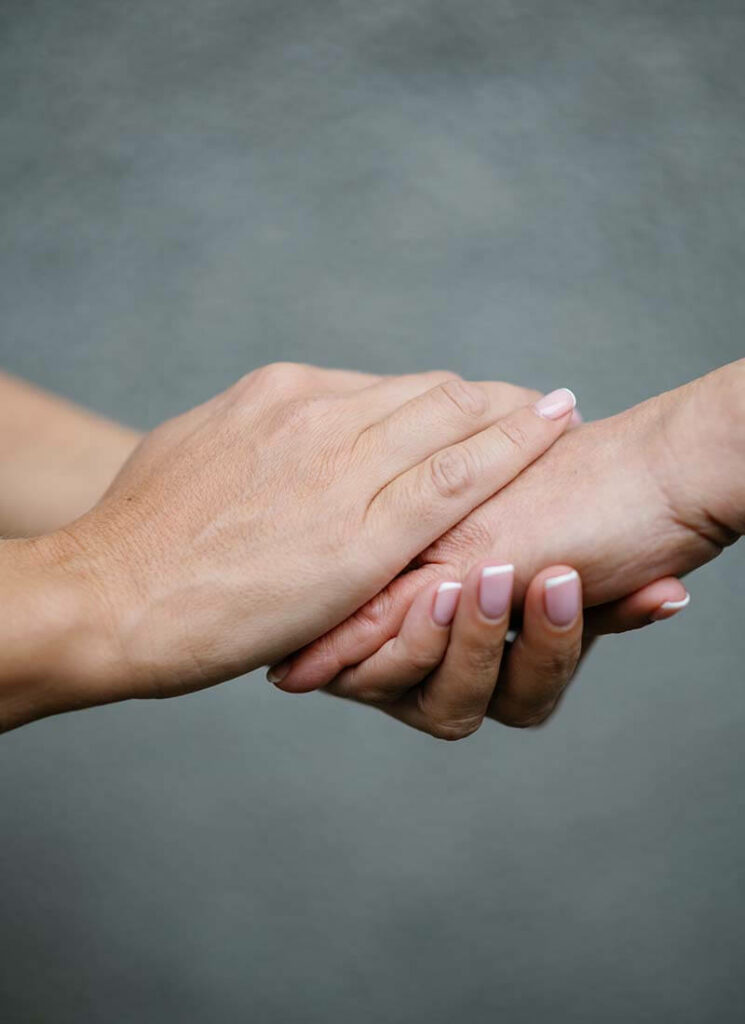 In-home caregiver holding hand of Cape Cod MA senior recovering from a skin infection.