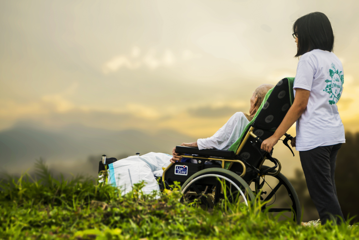 Hospice caregiver with senior outdoors viewing a beautiful sunset.